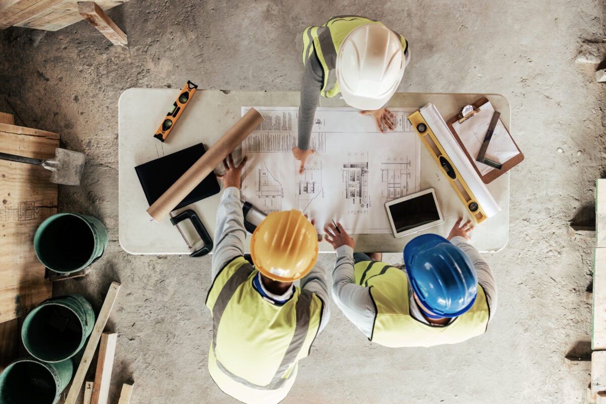 Top view, construction workers or blueprint planning in house, home or office building in real estate, property or architecture innovation. Men, engineering woman or construction site people or ideas.